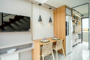 Uma cozinha moderna com área de refeições, TV na parede e geladeira embutida.