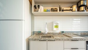 A kitchen with a granite countertop, a sink, a coffee maker, and a water dispenser.