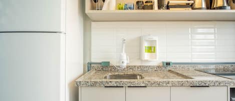 A kitchen with a granite countertop, a sink, a coffee maker, and a water dispenser.