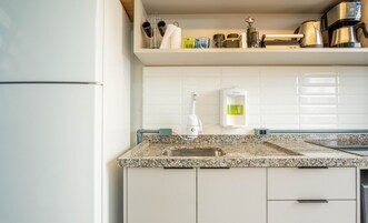 Uma cozinha com bancada de granito, pia, cafeteira e filtro de água.