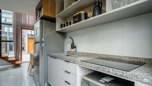Una cocina moderna con un refrigerador de acero inoxidable, encimera de granito y estantes empotrados.