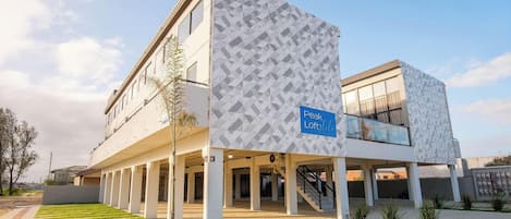 A building with a geometric facade, a sign indicating 'Peak Loftetil,' and a covered parking area.
