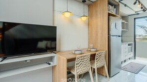 A modern kitchen with a built-in refrigerator, wooden cabinets, and a dining area with two chairs.