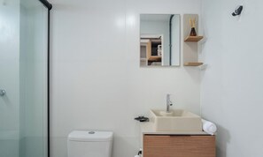 Een badkamer met toilet, wastafel, spiegel en douche.