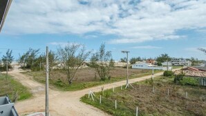 Paesaggio rurale con una strada sterrata, vegetazione rada e alcuni edifici in lontananza.