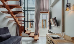 A modern interior with a wooden staircase, a dining area, and a flat-screen TV mounted on the wall. - Loft w/ Balcony 50m From the Beach Plo0004 (Jaguaruna)