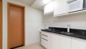 A kitchen with white cabinets, a black countertop, a stove, and a microwave. - 1BR Apartment, Self-check-in, Asa Norte Nor0203 (Brasília)