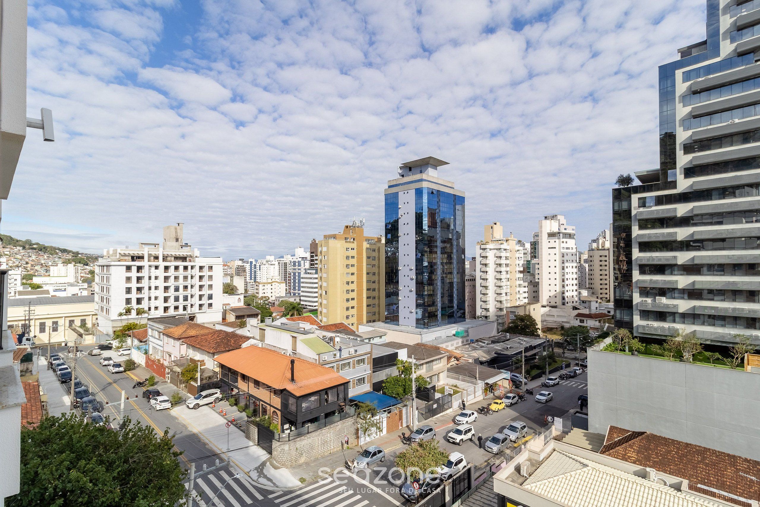 Un paisaje urbano con edificios modernos, cielo despejado y una calle con coches.