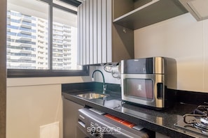 Una cocina compacta con microondas integrado, fregadero y lavavajillas.