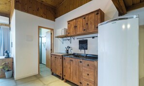 Una cocina compacta con armarios de madera, microondas integrado y un refrigerador.