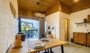 A wooden dining area with a table set for two, a hammock, and a view of the outdoors. - Modern Loft w/ Balcony Near Beach Nde0003 (Florianópolis)