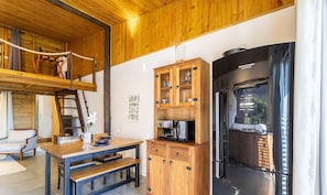 A wooden interior with a dining area, a refrigerator, and a loft space. - New Loft With Garden Terrace and Garden Nde0001 (Florianópolis)