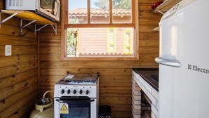 A compact kitchen with a gas stove, a microwave, and a refrigerator. - Cozy Cabin 10 min From Praia do Rosa Prj025 (Imbituba)