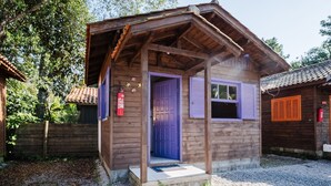 A wooden cabin with a purple door and shutters, a small porch, and a gravel driveway. - Cozy Cabin 10 min From Praia do Rosa Prj025 (Imbituba)