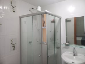 Ett badrum med en duschkabin med glasväggar, en vit tvättställ och en spegel ovanför tvättstället.