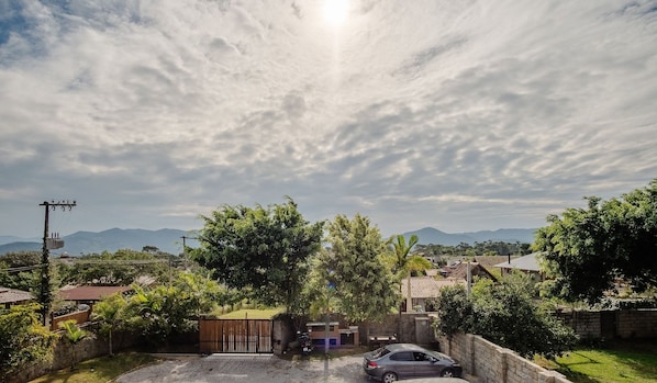 A residential area with houses, a car, and mountains in the background. - Comfortable Retreat at Praia do Rosa Prn0002 (Imbituba)