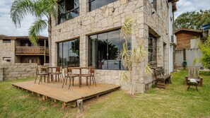 Un edificio de piedra con terraza de madera y mobiliario exterior.