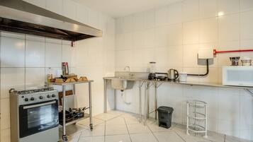 Una cocina con estufa, horno y pileta de acero inoxidable, un salpicadero de azulejos y una cubierta de encimera blanca.
