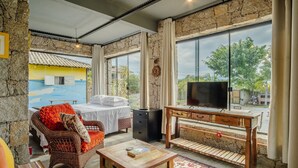 Une pièce confortable avec un lit, un fauteuil en osier, une table en bois et un téléviseur.