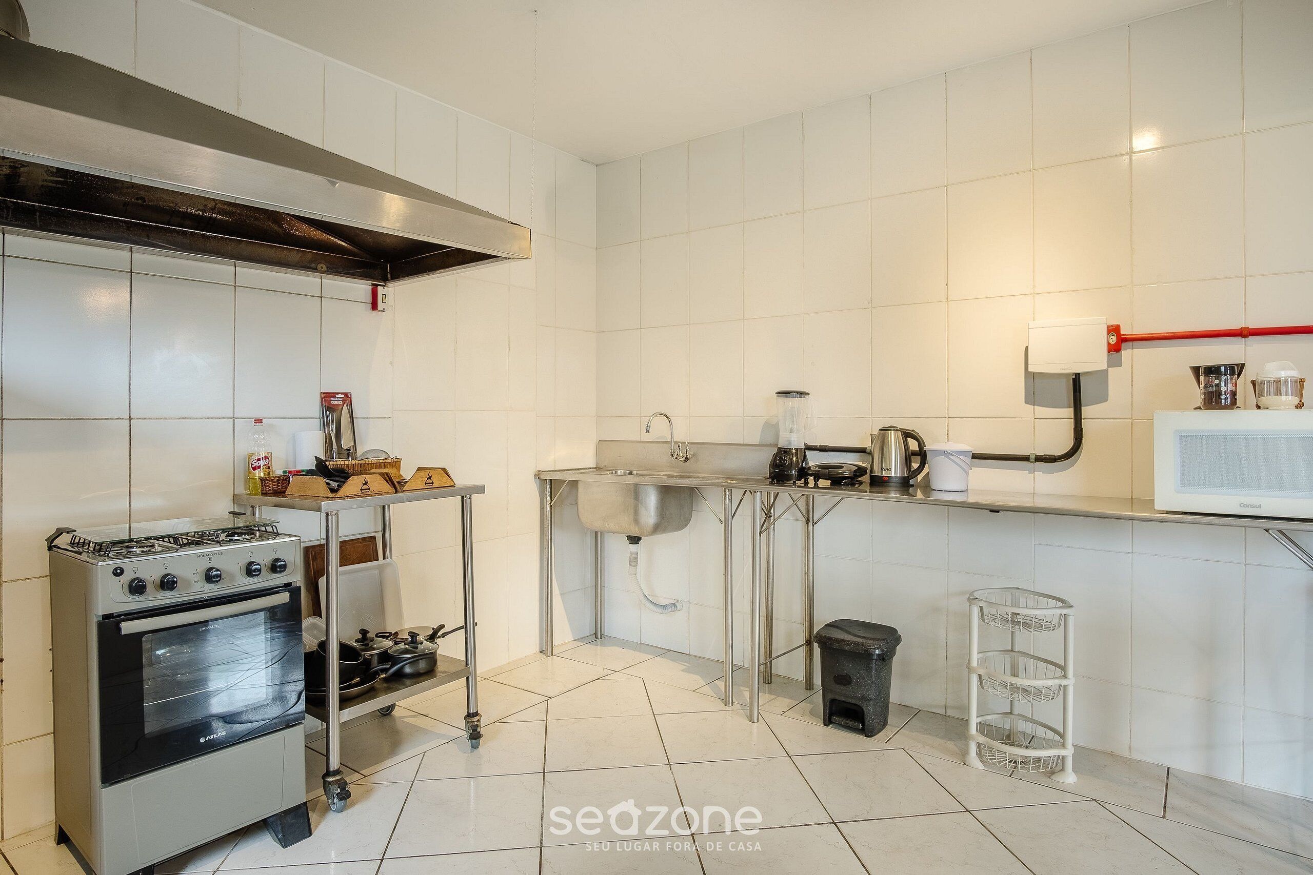 Eine Küche mit Edelstahlherd, Backofen und Spüle, einer gefliesten Spritzschutzwand und einer weißen Arbeitsplatte.