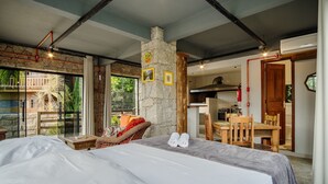 Une chambre avec un grand lit, un coin repas avec des meubles en bois et une cuisine équipée d’une cuisinière.
