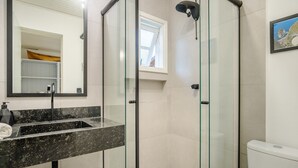 A modern bathroom with a glass-enclosed shower, a marble sink, and a toilet. - Charming House Just Minutes From the Beach Prn0003 (Imbituba)