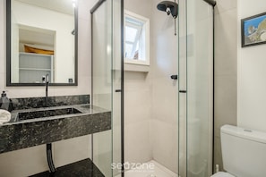 A modern bathroom with a glass-enclosed shower, a marble sink, and a toilet. - Charming House Just Minutes From the Beach Prn0003 (Imbituba)