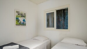 A room with two single beds, a poster on the wall, and a window with a view of a tree. - Charming House Just Minutes From the Beach Prn0003 (Imbituba)