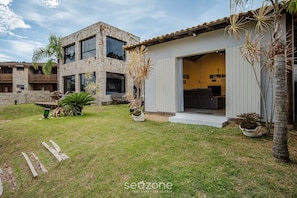 A two-story house with a stone facade, a balcony, and a small garden with palm trees. - Charming House Just Minutes From the Beach Prn0003 (Imbituba)