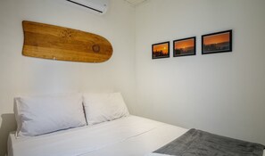 A bedroom with a bed, white bedding, a wooden headboard, and three framed pictures on the wall. - Charming House Just Minutes From the Beach Prn0003 (Imbituba)
