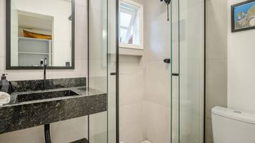 Un baño moderno con ducha de mampara de vidrio, lavabo de mármol e inodoro.