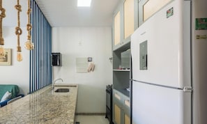 Eine kompakte Küche mit Einbauherd, Kühlschrank und Spüle.