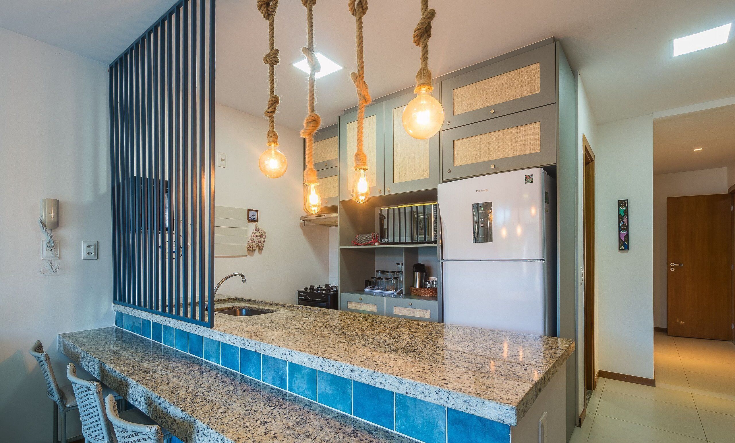 Una cocina moderna con encimeras de granito, un lavaplatos integrado y un refrigerador.