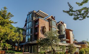 A multi-story building with a mix of glass and wood facade, balconies, and a prominent sculpture. - 2 BR Apartment Near Hard Rock Cafe Gramado Dms0106 (Gramado)