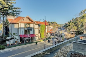 A street view with a Hard Rock Cafe, a building with a red awning, and a clear sky. - 2 BR Apartment Near Hard Rock Cafe Gramado Dms0106 (Gramado)