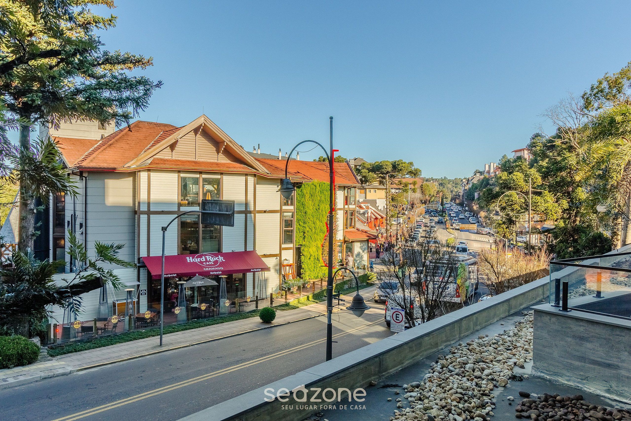 A street view with a Hard Rock Cafe, a building with a red awning, and a clear sky.