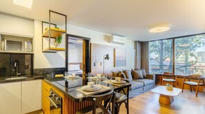 A modern kitchen with a microwave, stove, and dining area with a table set for two. - 2 BR Apartment Near Hard Rock Cafe Gramado Dms0106 (Gramado)