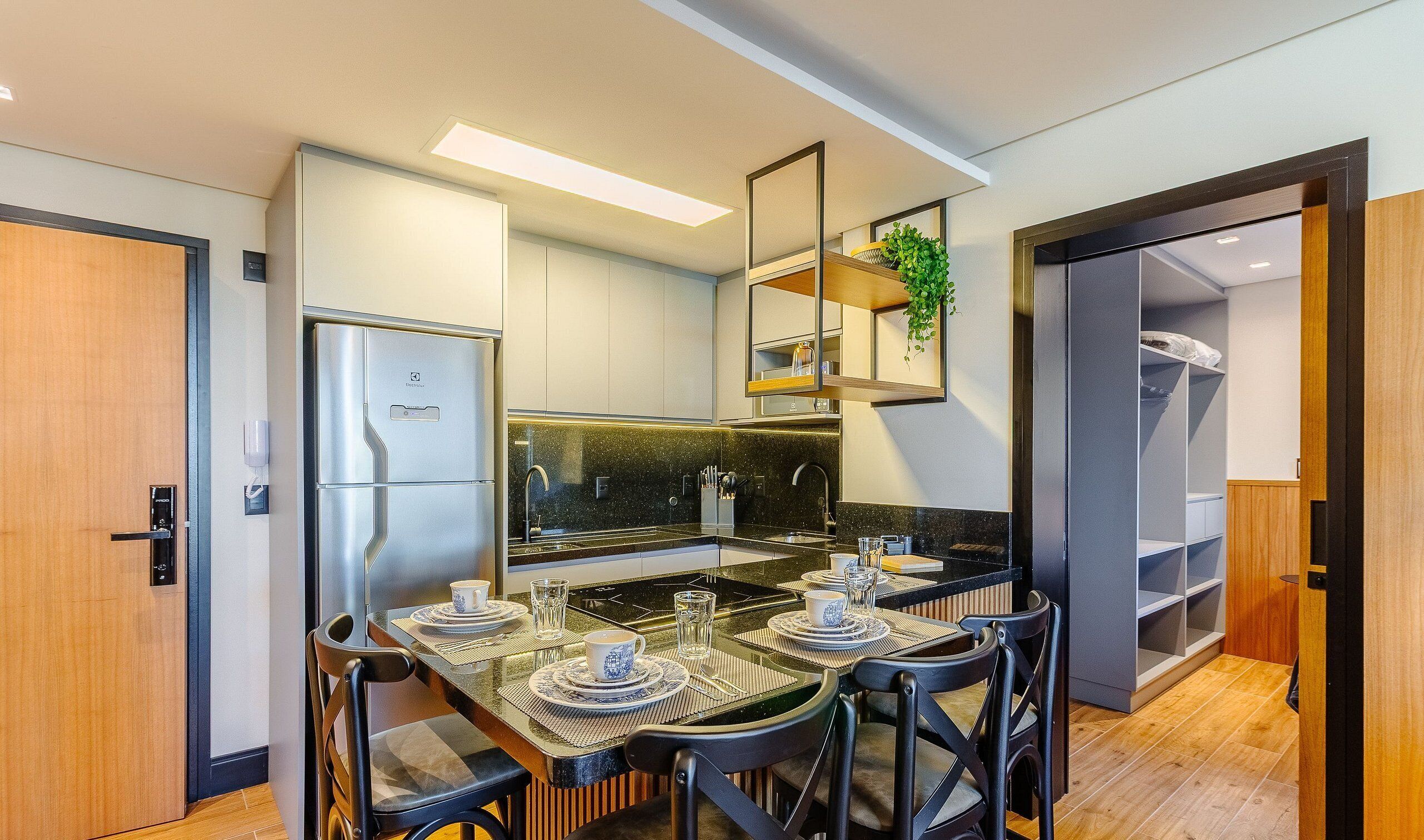 Een moderne keuken met een inbouwkoelkast, een eettafel voor vier personen en een klein kookeiland met een spoelbak.