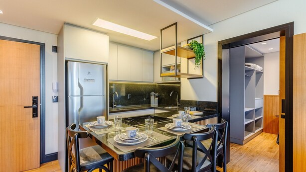Una cocina moderna con refrigerador empotrado, una mesa de comedor lista para cuatro personas y una pequeña isla con pileta.