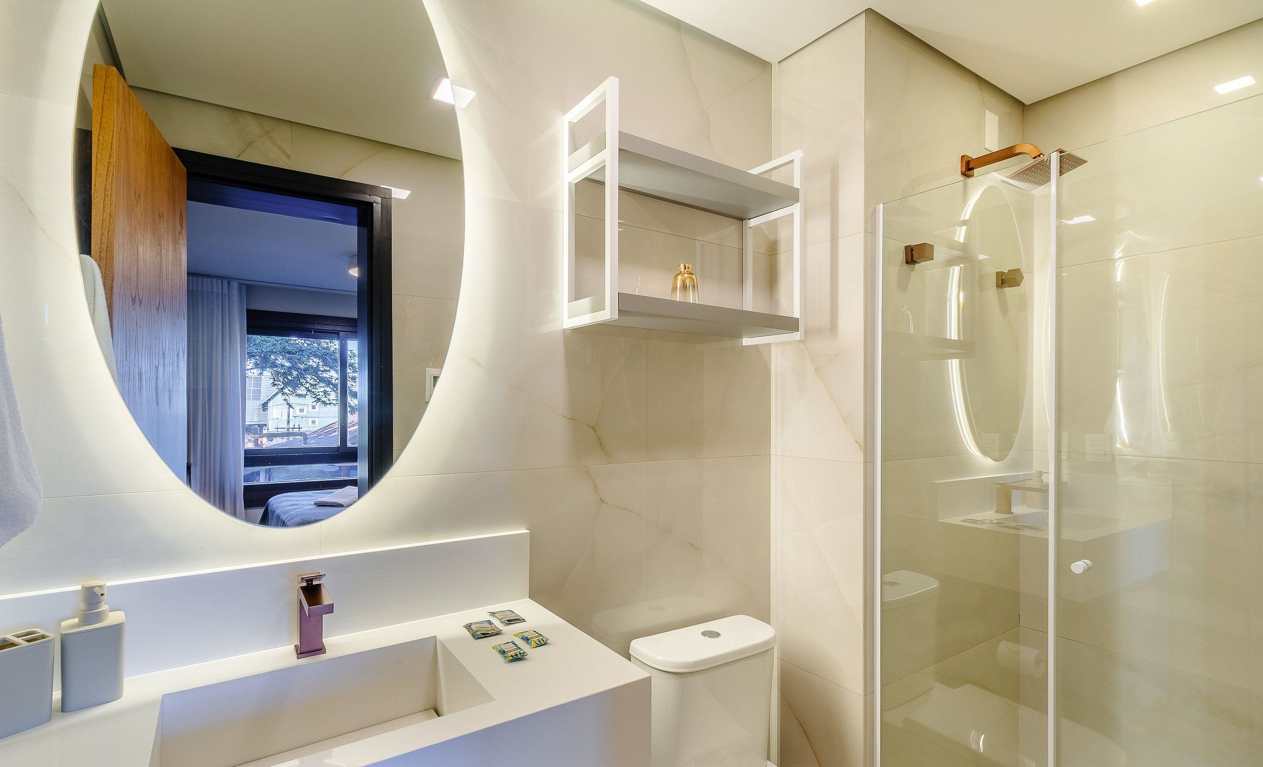 A modern bathroom with a curved mirror, a glass-enclosed shower, and a white sink.