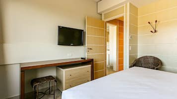 Een hotelkamer met een bed, een bureau met stoel, een televisietoestel en een kledingkast.