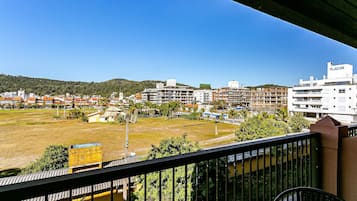 A balcony with a view of a residential area, including buildings and a hill.