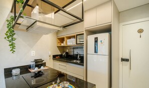 Eine kompakte Küche mit Einbauherd, Mikrowelle und Kühlschrank.