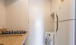 Eine kompakte Küche mit Gasherd, Waschmaschine und Kühlschrank.