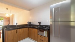 Cozinha moderna com armários de madeira, geladeira de aço inoxidável, forno embutido e micro-ondas.