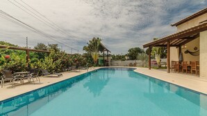 Piscina com espreguiçadeiras e área de estar coberta.