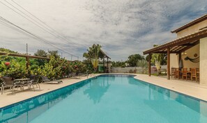 A swimming pool with lounge chairs and a covered seating area.