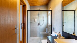 Een moderne badkamer met een douchecabine, toilet en wastafel met aanrechtblad.