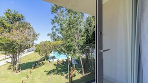 Ein Balkon mit Blick auf ein Schwimmbecken und die umliegende Bepflanzung.