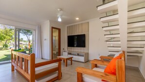 Ein modernes Wohnzimmer mit Flachbildfernseher, Holzmöbeln und einer Treppe.